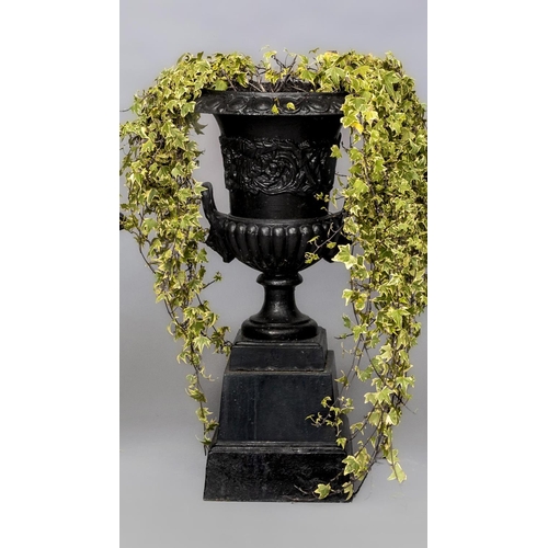 469 - A CAST IRON GARDEN URN of half fluted campana form with lion mask loop handles, the body with a band... 