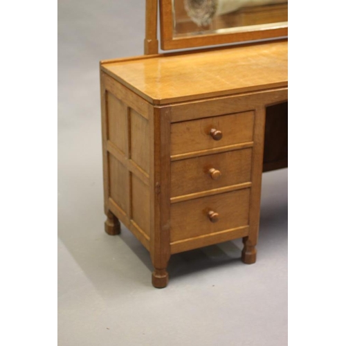 595 - A ROBERT THOMPSON ADZED OAK DRESSING TABLE, the bevelled oblong swing mirror on turned faceted suppo... 