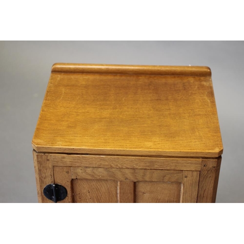 602 - A ROBERT THOMPSON ADZED OAK BEDSIDE CABINET of canted multi-panelled oblong form, the moulded edged ... 