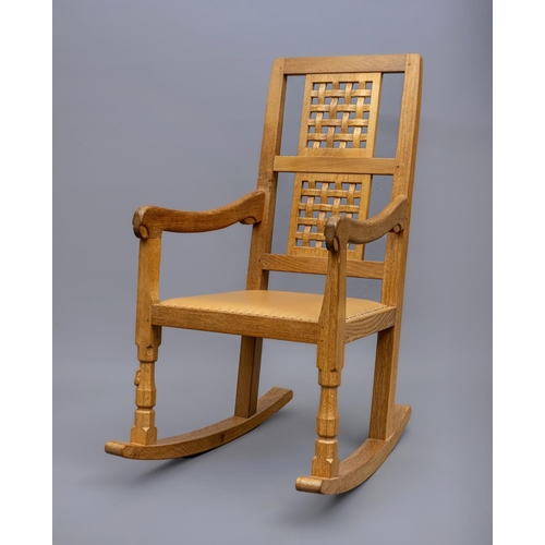 604 - A ROBERT THOMPSON OAK ROCKING CHAIR, the tapering back with straight top rail over a pierced basket ... 