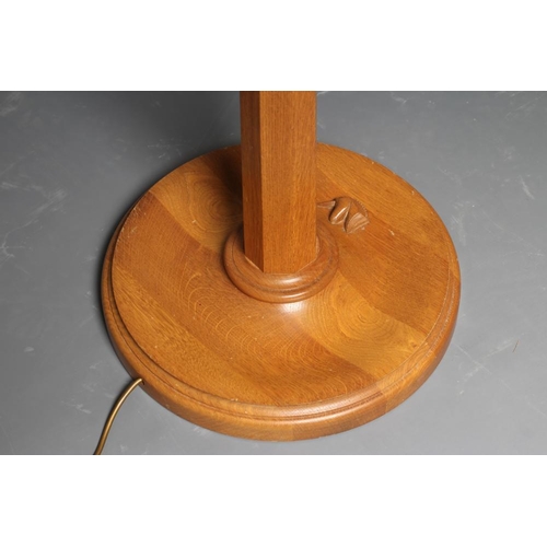 606 - AN OAK STANDARD LAMP BY GEOFF GELL OF COXWOLD, the tapering faceted stem on on moulded edged dished ... 