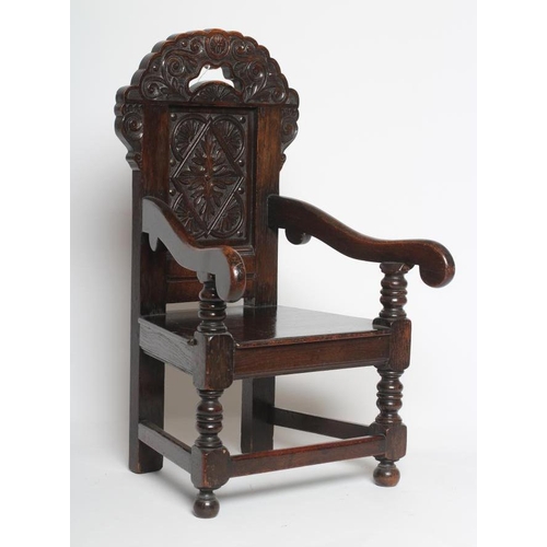 617 - A CHILDS JOINED OAK ARMCHAIR, in 17th style, the panelled back carved with foliage and surmounted by... 