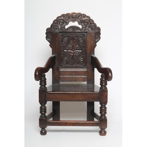 617 - A CHILDS JOINED OAK ARMCHAIR, in 17th style, the panelled back carved with foliage and surmounted by... 