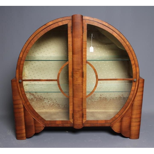 625 - AN ART DECO WALNUT DISPLAY CABINET of circular form with two astragal glazed doors with turned brass... 