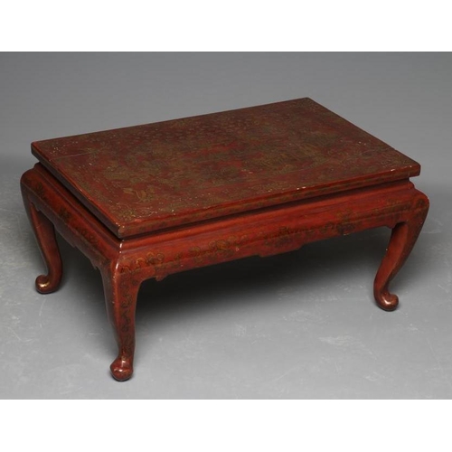 648 - A CHINESE RED LACQUERED LOW TABLE, 20th century, the oblong top gilded with figures in a garden with... 