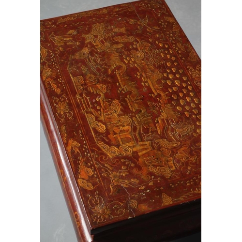 648 - A CHINESE RED LACQUERED LOW TABLE, 20th century, the oblong top gilded with figures in a garden with... 