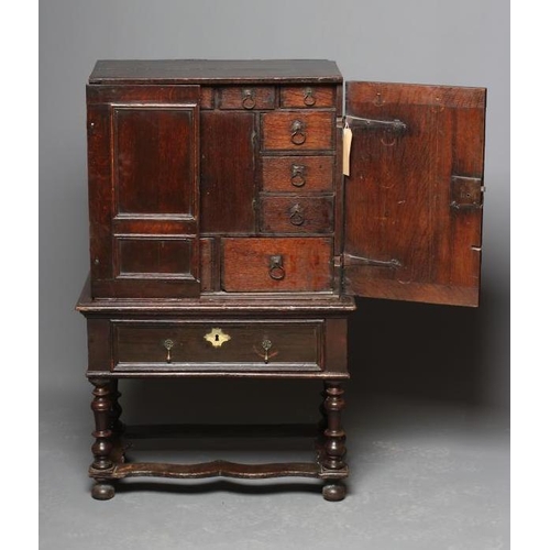 661 - AN OAK CHEST ON STAND, the chest with two twin panel doors enclosing a central cupboard and twelve s... 