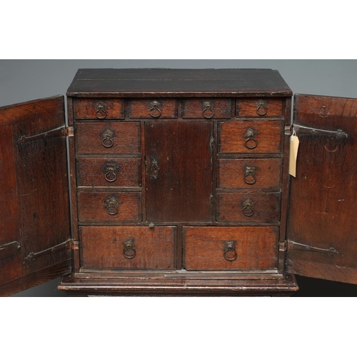 661 - AN OAK CHEST ON STAND, the chest with two twin panel doors enclosing a central cupboard and twelve s... 