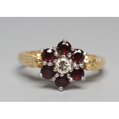 170 - A GARNET AND DIAMOND CLUSTER RING, the central brilliant cut diamond with a border of six point set ... 