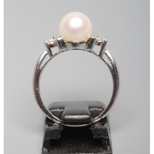 175 - A CULTURED PEARL RING, the white pearl set to shoulders line set with three small diamonds to a plai... 