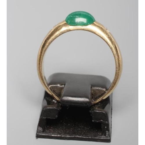 198 - AN EMERALD AND DIAMOND RING, the oval cabochon polished emerald tension set and flanked by two gypsy... 