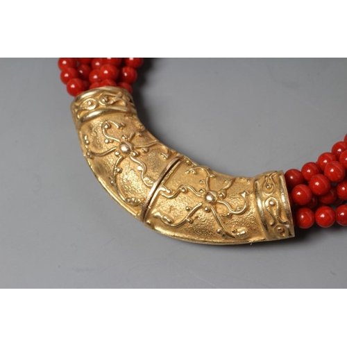 201 - A SIX STRAND CORAL BEAD BRACELET, the strands set into a crescent shaped panel clasp chased with scr... 