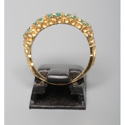 205 - A FIVE STONE EMERALD RING, the graduated oval facet cut stones in claw and rub-over settings to leaf... 