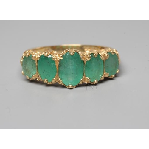 205 - A FIVE STONE EMERALD RING, the graduated oval facet cut stones in claw and rub-over settings to leaf... 