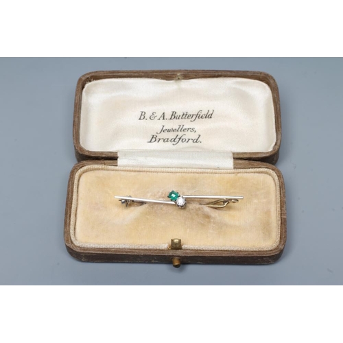 220 - AN EMERALD AND DIAMOND BAR BROOCH, the circular facet cut stones claw set to an asymetrical knife ed... 