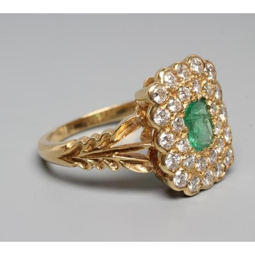 246 - AN EMERALD AND DIAMOND CLUSTER DRESS RING, the oblong facet cut emerald claw set to a double border ... 