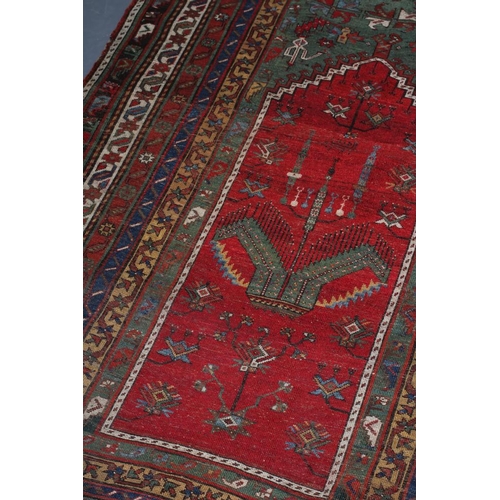 329 - A TURKISH PRAYER RUG, the green field with stepped red niche with flowers and candles, within a mult... 