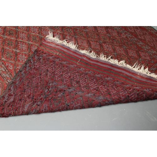 442 - A PERSIAN TRIBAL RUG, the soft red ground with trellis patterned field in shades of grey, within a z... 