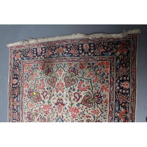 444 - A PERSIAN RUG, 20th century, the ivory and camel floral field centred by a navy blue gul all in shad... 