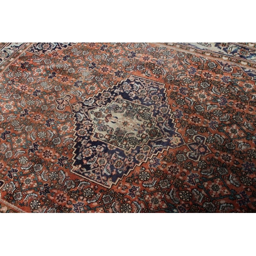 445 - A PERSIAN RUG, 20th century, the red floral field with navy blue centre gul and spandrels, with navy... 