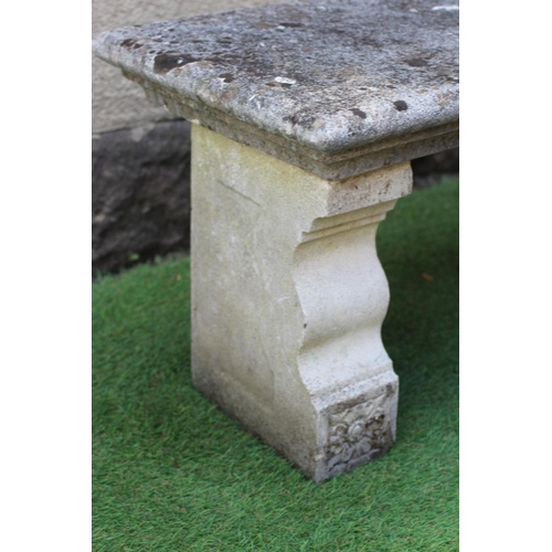 741 - A CAST STONE BENCH, the moulded edged oblong seat raised on flower moulded square section end supppo... 