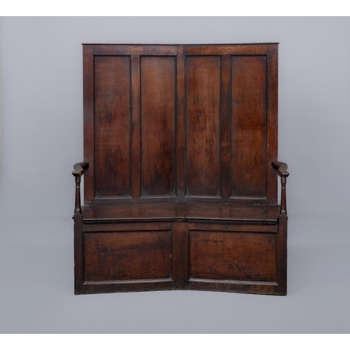 871 - A GEORGIAN JOINED OAK PANELLED BOX SETTLE, 18th century, of angled form, the four panelled back with... 