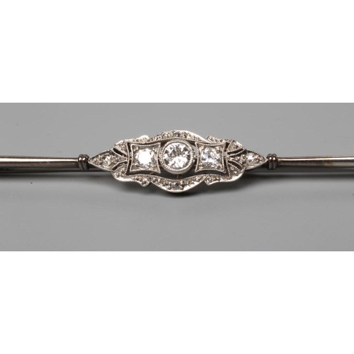 184 - A DIAMOND BAR BROOCH centred by a collet set brilliant cut stone of approximately 0.20cts flanked by... 