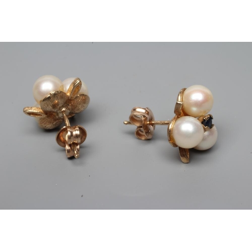 185 - A PAIR OF CULTURED PEARL EAR STUDS, the three pearls peg set and centred by a small sapphire with th... 