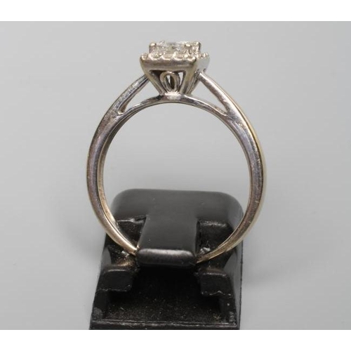 202 - A DIAMOND CLUSTER RING, the central square cut stone claw set to an open border of sixteen small rou... 