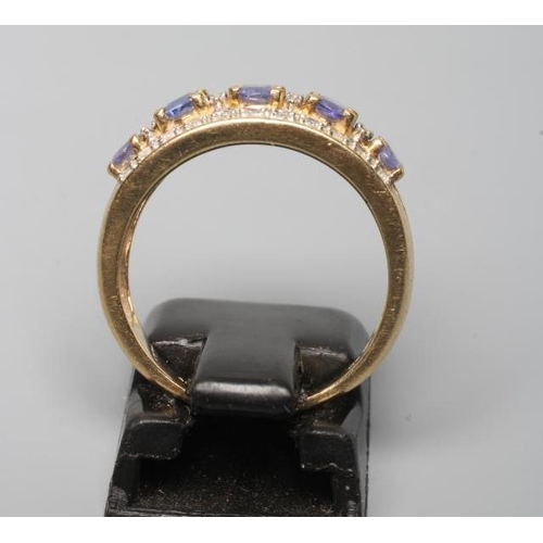 215 - A TANZANITE AND DIAMOND HALF HOOP RING, the five graduated oblong facet cut tanzanites claw set to b... 