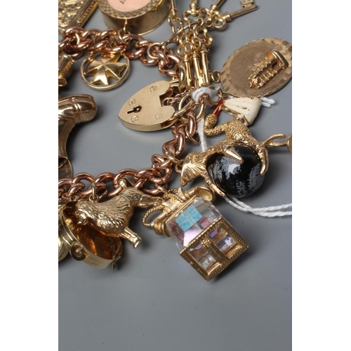 265 - A 9CT GOLD CURB LINK CHAIN BRACELET with padlock fastener, hung with eighteen charms including eagle... 