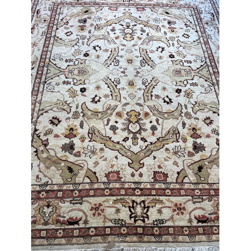 373 - A PERSIAN STYLE WOOL CARPET, the ivory ground with all over bold foliate pattern in pale green and s... 