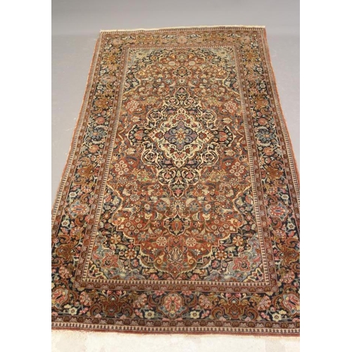 415 - A PERSIAN RUG, early 20th century, the red floral field with central navy blue gul, navy blue main b... 