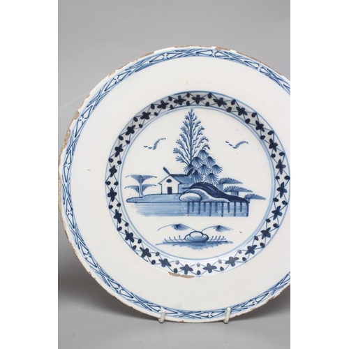 29 - AN ENGLISH DELFT PLATE, c.1780, centrally painted in blue with a landscape with a house and two flig... 