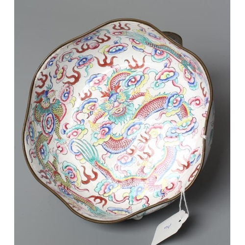 652 - A CANTON ENAMEL BOWL of lobed circular form, painted in bright colours with dragons on a white groun... 