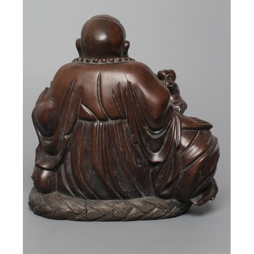 653 - A CHINESE CARVED HARDWOOD BUDDAH, seated wearing a long bead necklace and with three children in att... 