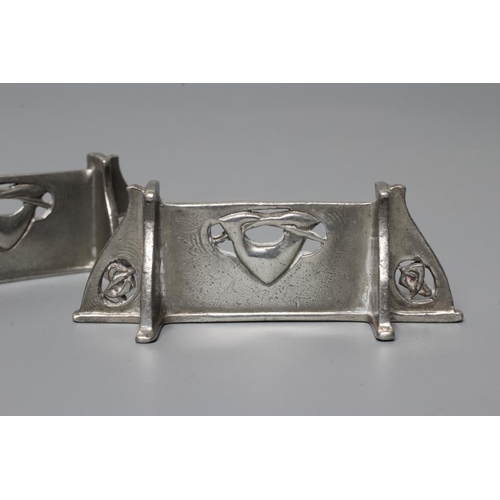 657 - ARCHIBALD KNOX FOR LIBERTY - a pair of pewter knife rests, of oblong form and pierced with entrelacs... 