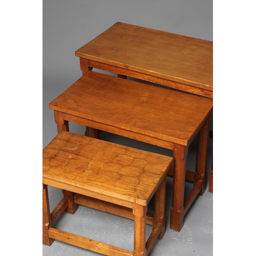 876 - A WILFRED HUTCHINSON (HUSTWAITE) NEST OF THREE ADZED OAK TABLES, the rounded oblong top raised of fa... 