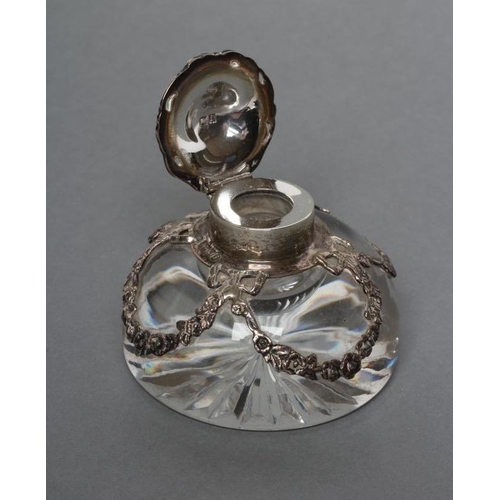 196 - AN EDWARDIAN SILVER MOUNTED HEAVY CLEAR GLASS DOMED INKWELL with star cut base, the mount with cast ... 