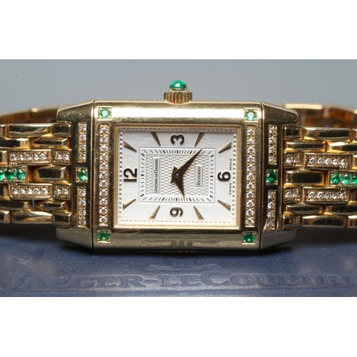 421 - A LADY'S JAEGER-LECOULTRE EMERALD AND DIAMOND REVERSO WRISTWATCH/BRACELET, the oblong silvered dial ... 