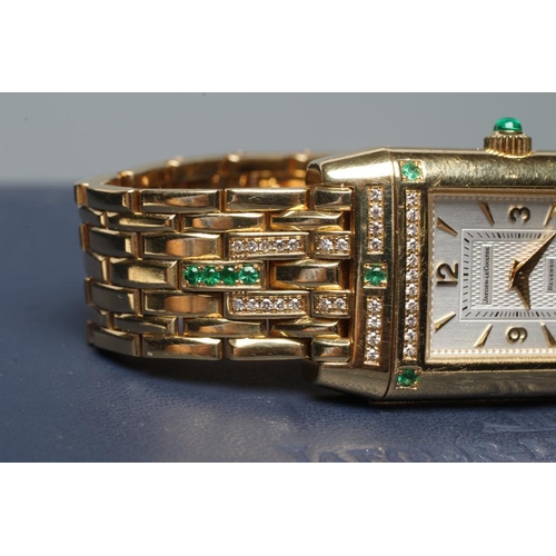 421 - A LADY'S JAEGER-LECOULTRE EMERALD AND DIAMOND REVERSO WRISTWATCH/BRACELET, the oblong silvered dial ... 