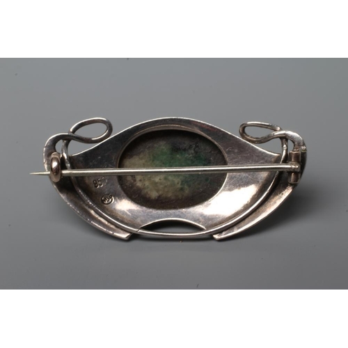 426 - A MURRLE BENNETT BROOCH, the shaded green glass oval cabochon in a planished whiplash and wing mount... 