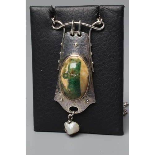 427 - A MURRLE BENNETT PENDANT, the mottled cream and green glass oval cabochon in a planished shaped oblo... 