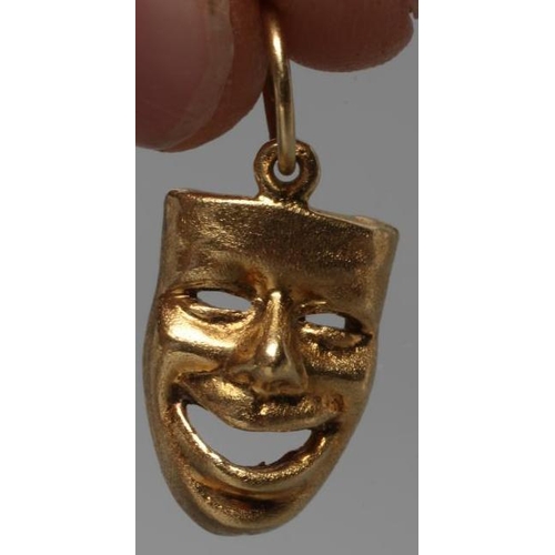 453 - A CHARM/PENDANT, stamped 750/GB, cast and pierced as the theatrical comedy mask with matt finish, to... 