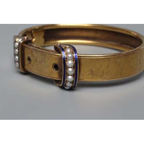 470 - A VICTORIAN STIFF HINGED BUCKLE BANGLE, the upper section with two seed pearl and blue enamel 