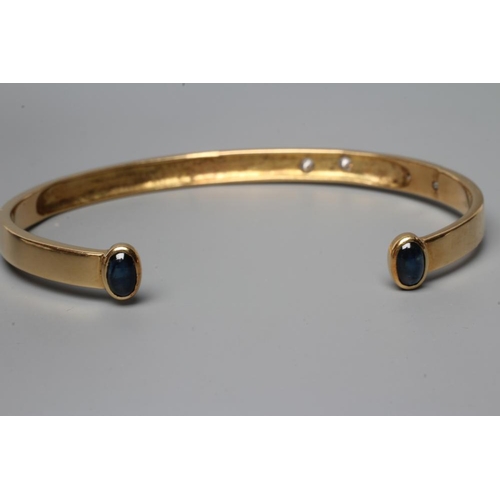 478 - A BANGLE, stamped 750, asymetrically set with four graduated round brilliant cut stones, each termin... 