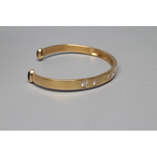 478 - A BANGLE, stamped 750, asymetrically set with four graduated round brilliant cut stones, each termin... 