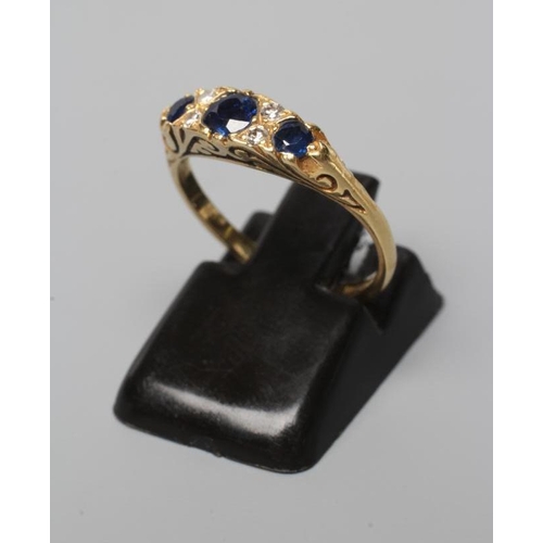 500 - A SEVEN STONE SAPPHIRE AND DIAMOND RING, with carved scroll shoulders and plain 18ct gold shank, Bir... 