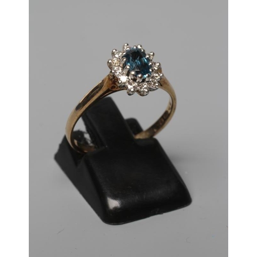 501 - A BLUE TOPAZ AND DIAMOND CLUSTER RING, the oval facet cut topaz claw set to a border of twelve small... 