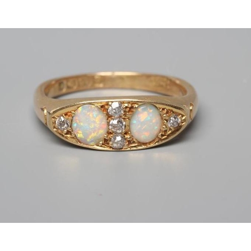 502 - AN EDWARDIAN OPAL AND DIAMOND RING, the eliptical panel set with two oval cabochon polished opals an... 